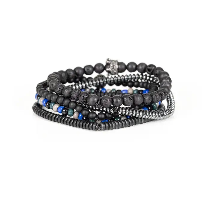 Black multi-layer men’s bracelet featuring lava stone beads, metallic hematite strands, crystal crown centerpiece, blue and white accent beads, and layered black bead details on a light background.