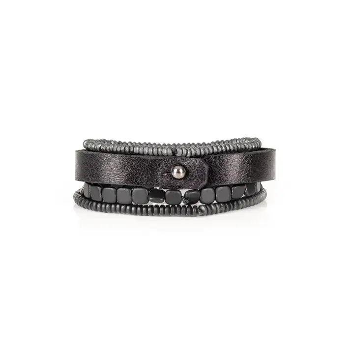 Black multi-layer men’s bracelet set featuring matte onyx beads, braided black rope, crystal cross centerpiece, gold chevron metal bar, and layered metallic accents on a light background.