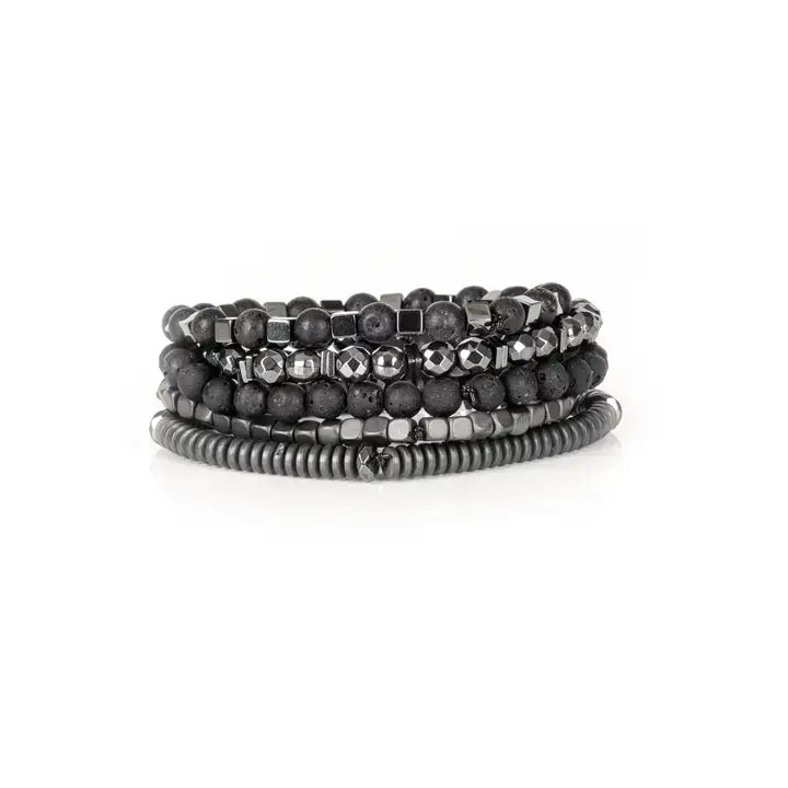 Black multi-layer men’s bracelet set featuring lava stone beads, faceted hematite stones, metallic cube accents, and layered gunmetal bead strands on a light background.