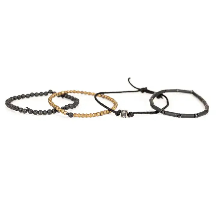 Black and gold multi-layer men’s bracelet featuring matte black tubular beads, faceted gold hematite strands, braided black cord, lava stone beads, and crystal accent detail on a light background.