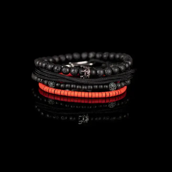 Men’s layered bracelet set featuring matte black lava stone beads, black braided cord, black onyx-style beads, gunmetal accent beads, a crown charm centerpiece, and vibrant red heishi beads, stacked in a bold contemporary luxury design on a white background.