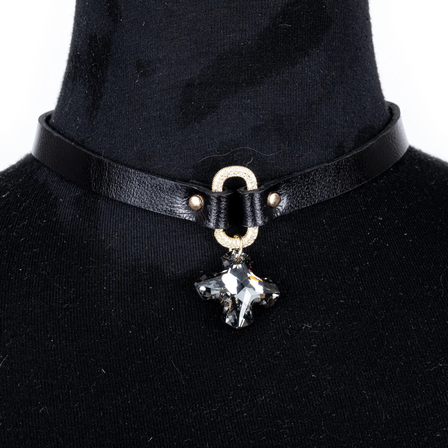 Black leather choker with a crystal oval connector and a faceted crystal cross pendant, displayed on a white background.