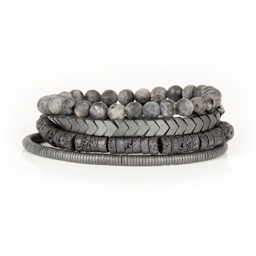 Men’s layered bracelet set featuring gray natural stone beads, gunmetal chevron metal beads, dark lava stone disc beads, and silver-tone coil wrap accents, stacked in a sleek monochromatic industrial luxury design on a white background.