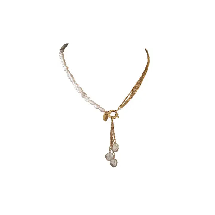 Asymmetrical gold necklace with freshwater pearl strand and chain tassel with pearl drops on white background.