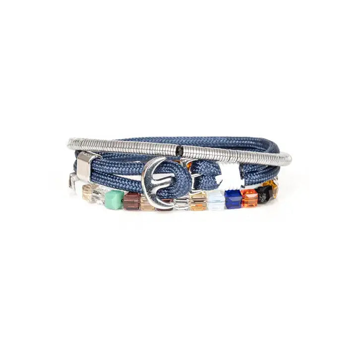 Men’s layered bracelet set featuring blue braided cord, silver-tone coil wrap, faceted crystal cube beads in blue, orange, gray, black, and clear tones, finished with polished metal accents in a modern luxury style on a white background.