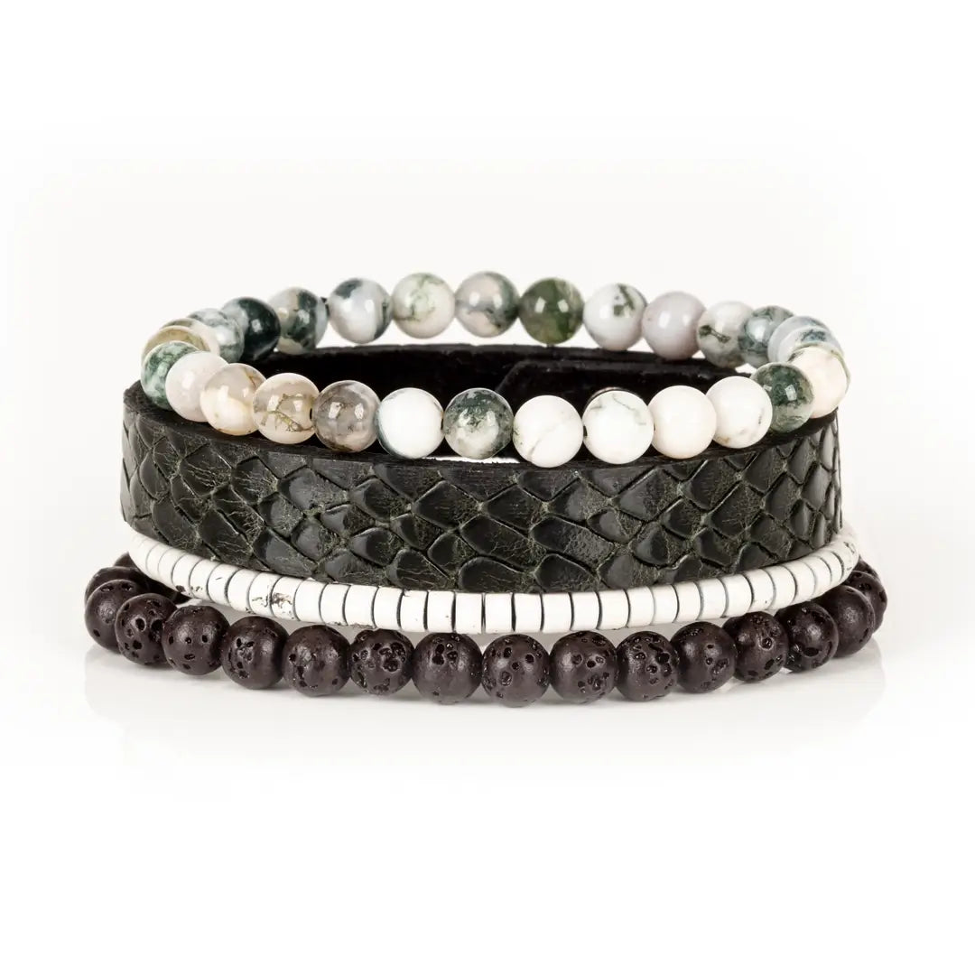 Men’s layered bracelet set featuring a black embossed leather cuff with a reptile-inspired texture, white howlite beads, green moss agate stone beads, white heishi beads, and dark lava stone beads, stacked in a sophisticated natural luxury design on a white background.