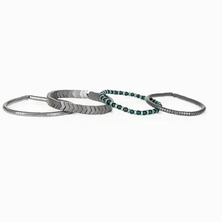 Men’s layered bracelet set featuring gunmetal chevron metal beads, black and turquoise beaded strands, dark hematite spacer beads, and silver-tone coil wrap accents, stacked in a modern industrial luxury design on a white background.