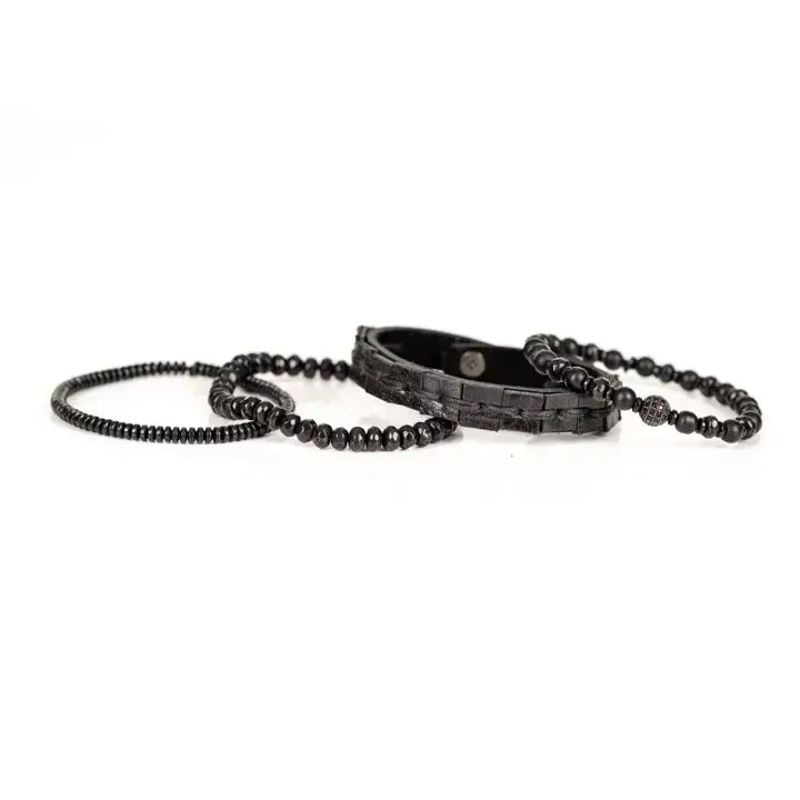 Black multi-layer men’s bracelet featuring woven leather band, matte onyx beads, faceted black crystal stones, crystal centerpiece accent, and hematite bead strand on a light background.