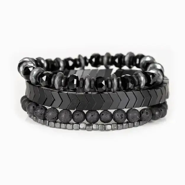 Men’s layered bracelet set featuring faceted black crystal beads, black and gray marbled stone beads, gunmetal chevron metal beads, matte black lava stone beads, and silver-tone hematite spacer beads, stacked in a bold monochromatic luxury design on a white background.