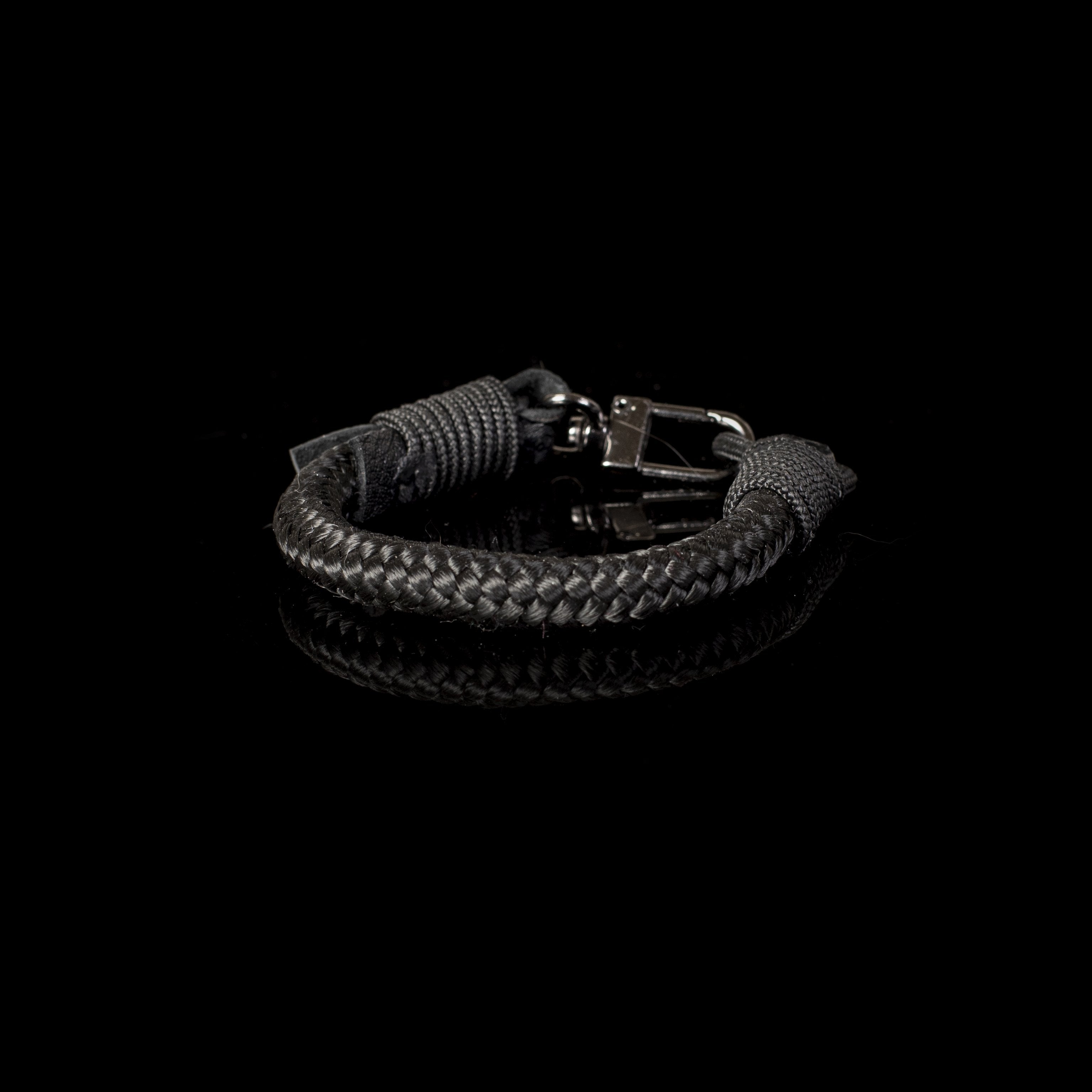 Handcrafted black braided leather bracelet with polished metal clasp displayed on a white background.