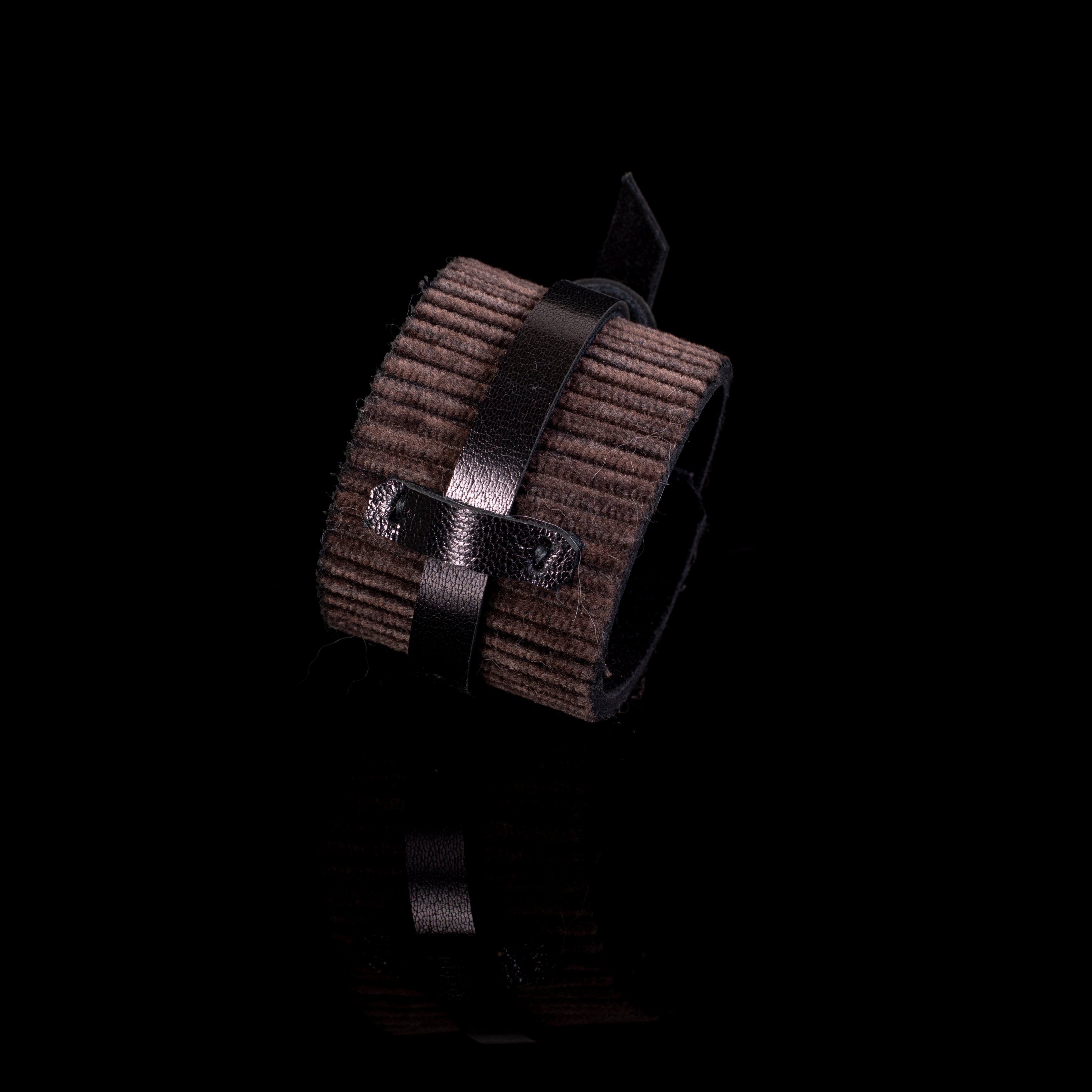 Brown ribbed leather cuff bracelet with central wrap strap detail and wide textured surface, handcrafted statement piece