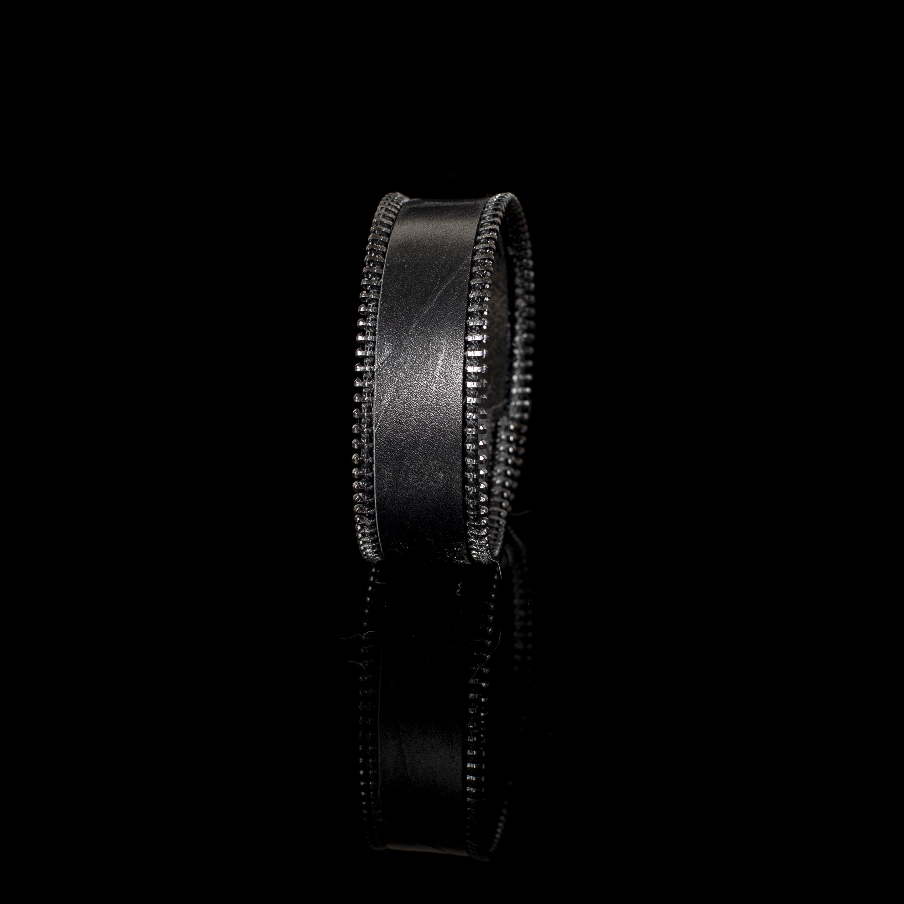 Wide black leather cuff bracelet featuring exposed zipper detailing along both edges in a handcrafted industrial-inspired design.
