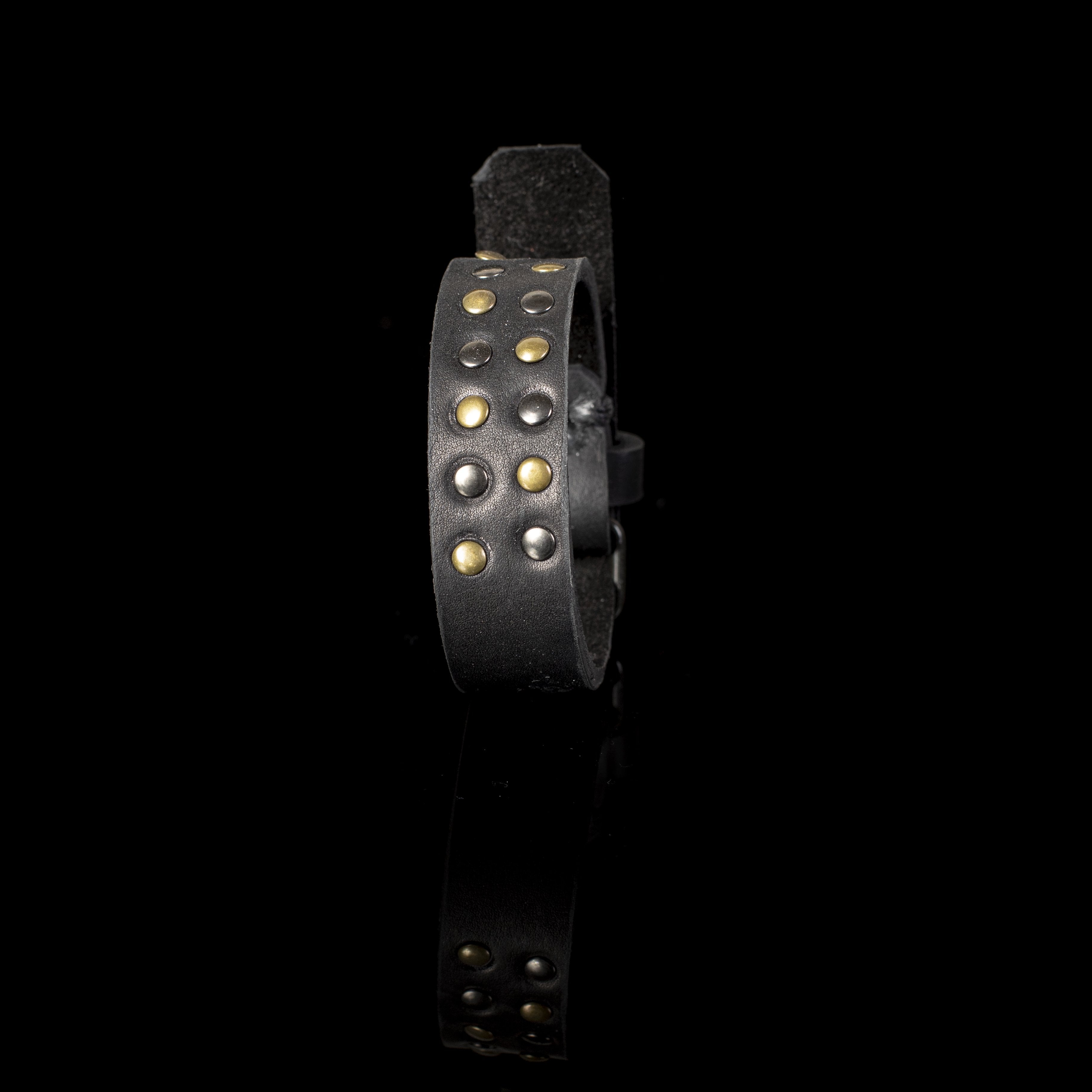 Handmade black leather cuff bracelet featuring antique brass and gunmetal studs with a wide statement design.