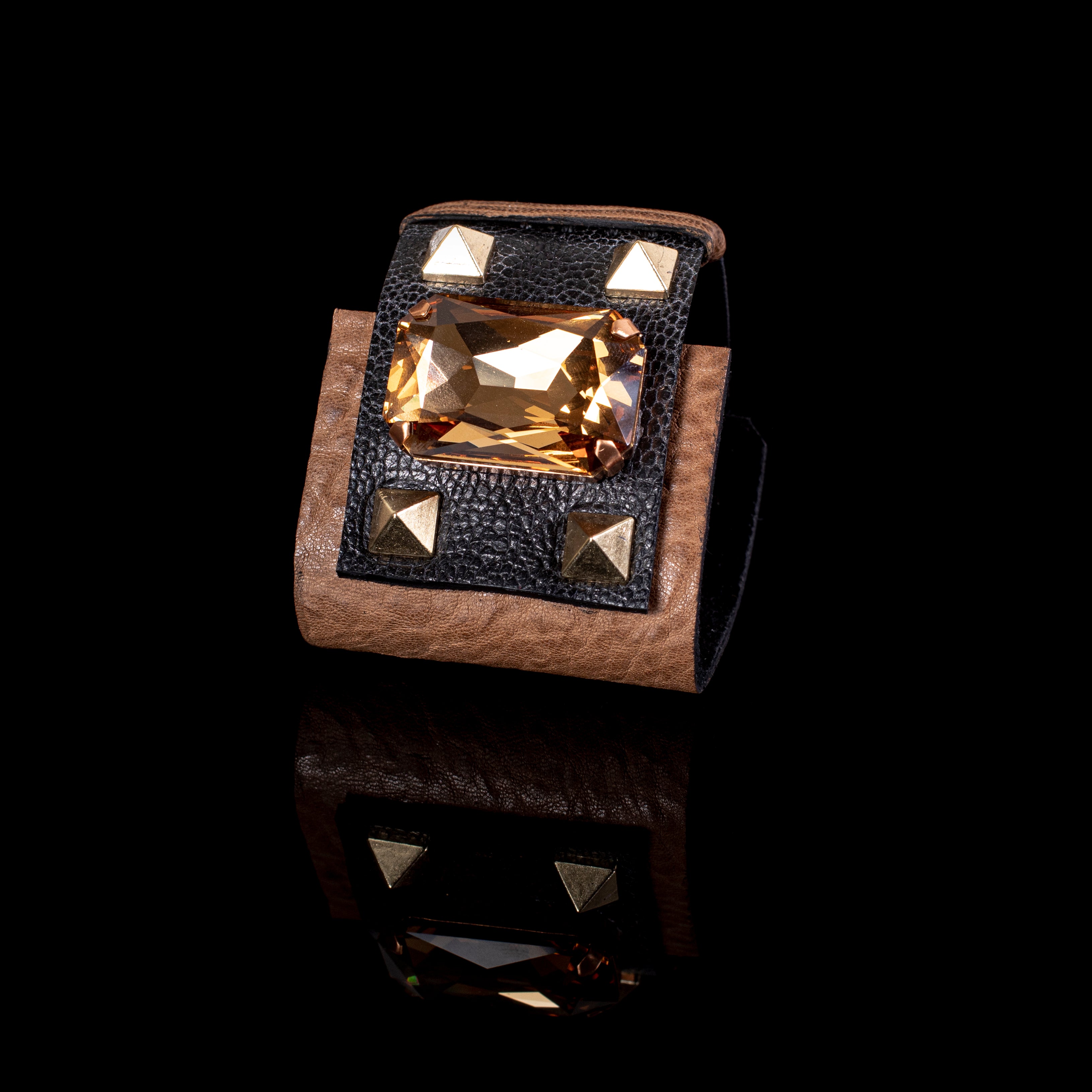 Brown leather cuff bracelet with large amber crystal centerpiece and gold stud accents, bold handcrafted statement piece