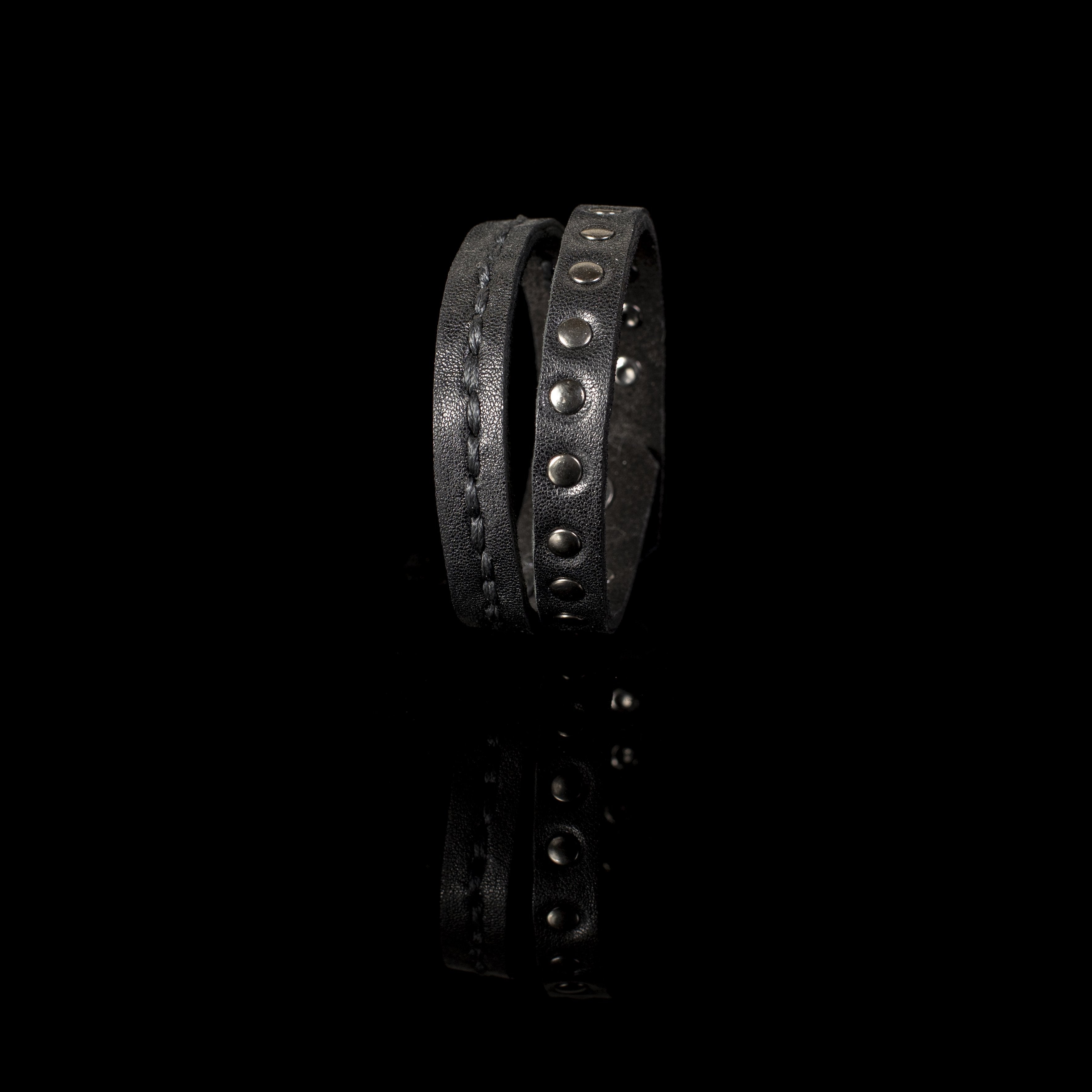 Men's double-wrap black genuine leather bracelet featuring hand-stitched detailing and gunmetal stud accents on a white background.