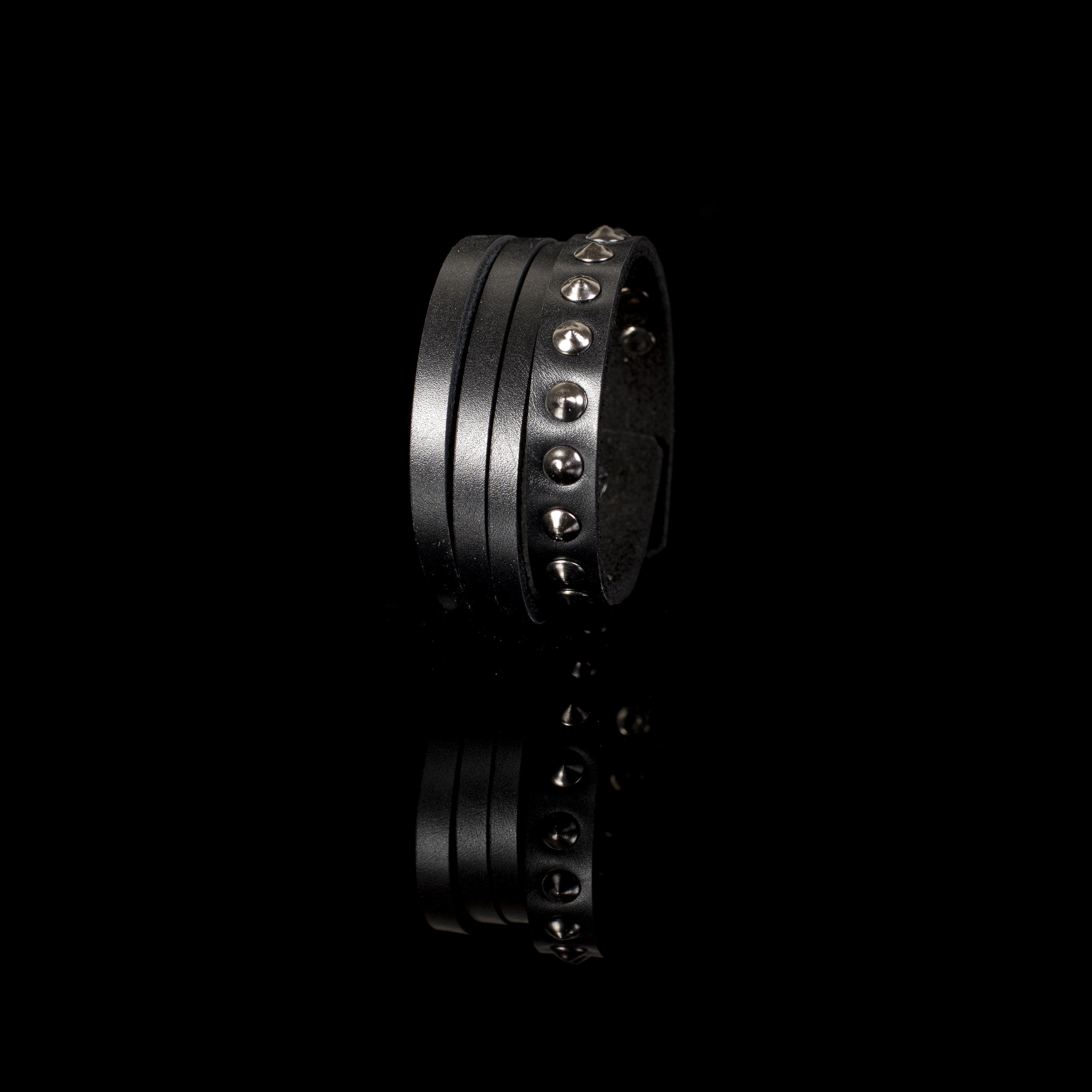 Men's multi-layer black genuine leather bracelet featuring gunmetal rivets, studded detailing, and adjustable snap-button closure on a white background.