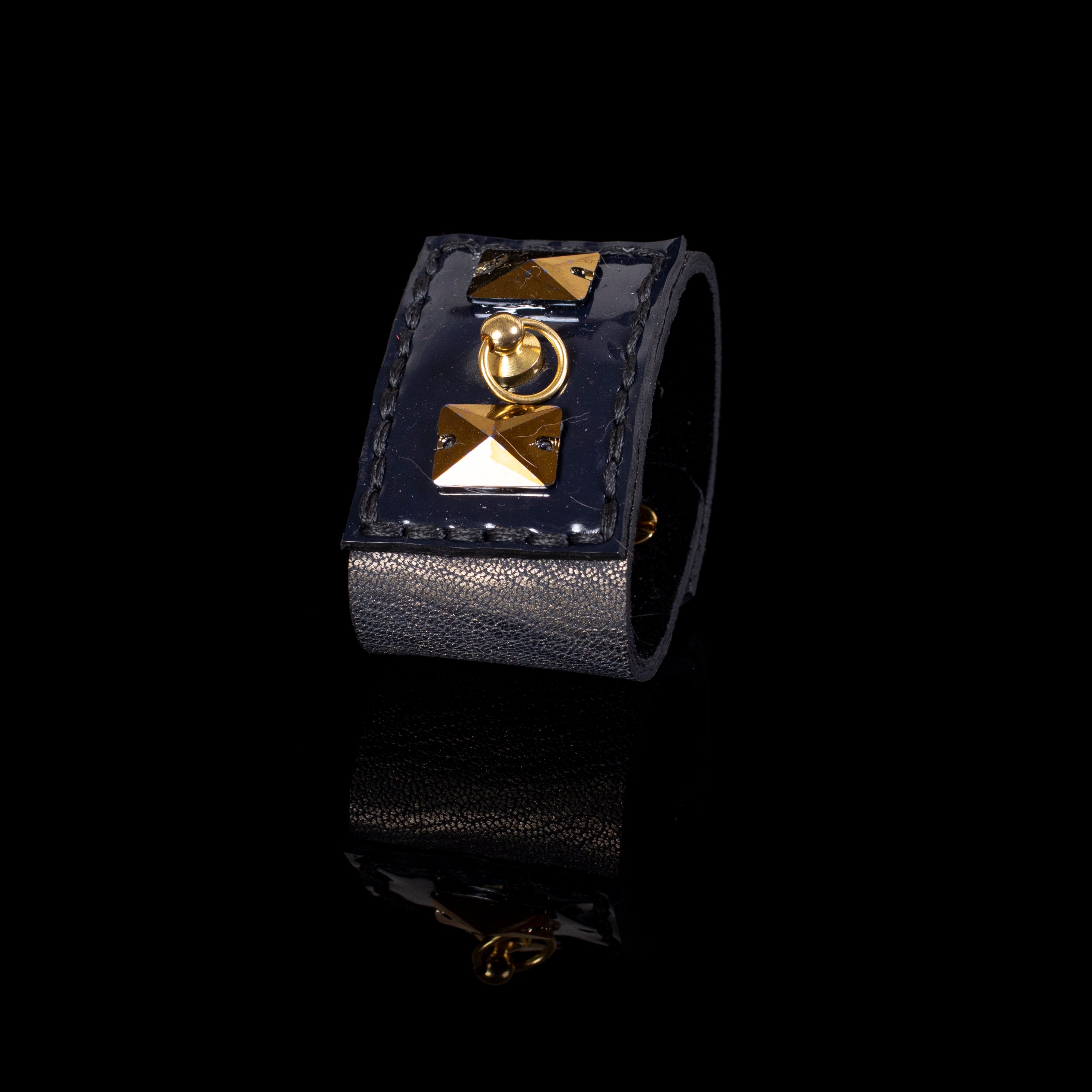 Wide black leather cuff bracelet with gold pyramid studs and central ring detail, bold statement bracelet for women