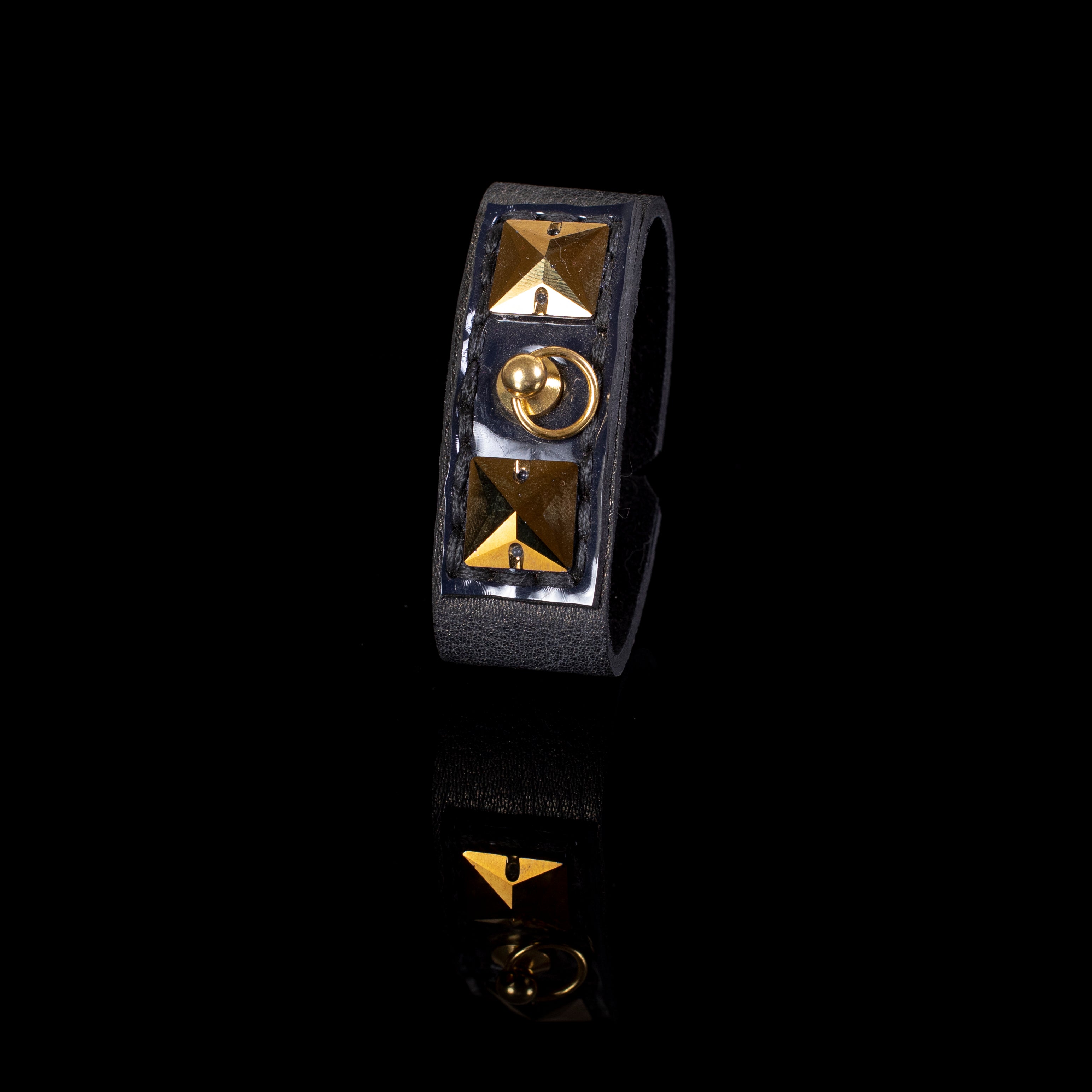 Slim black leather cuff bracelet with gold pyramid studs and central ring detail, narrow statement bracelet for women