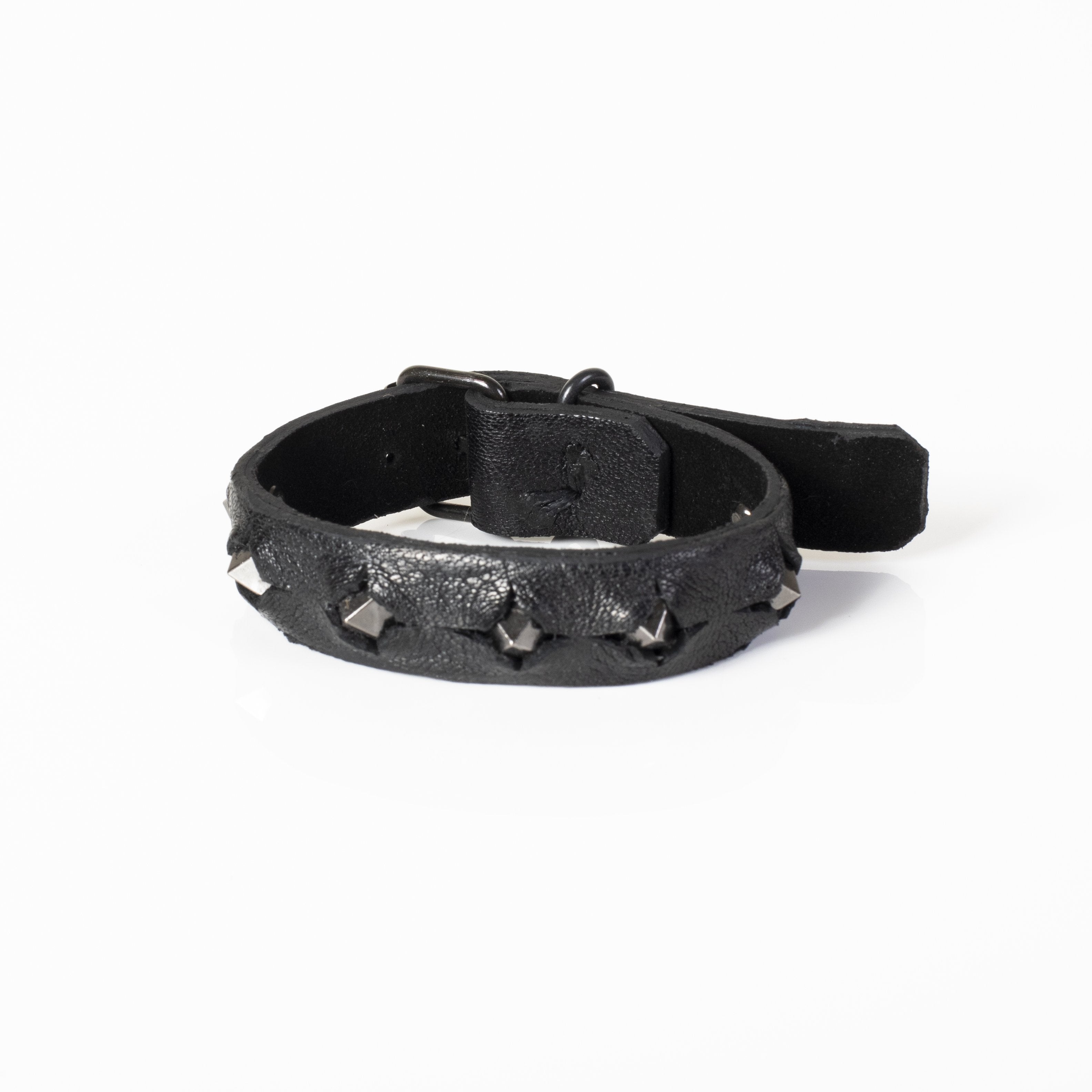 Men's black leather cuff bracelet featuring gunmetal pyramid studs and adjustable snap-button closure on a white background.