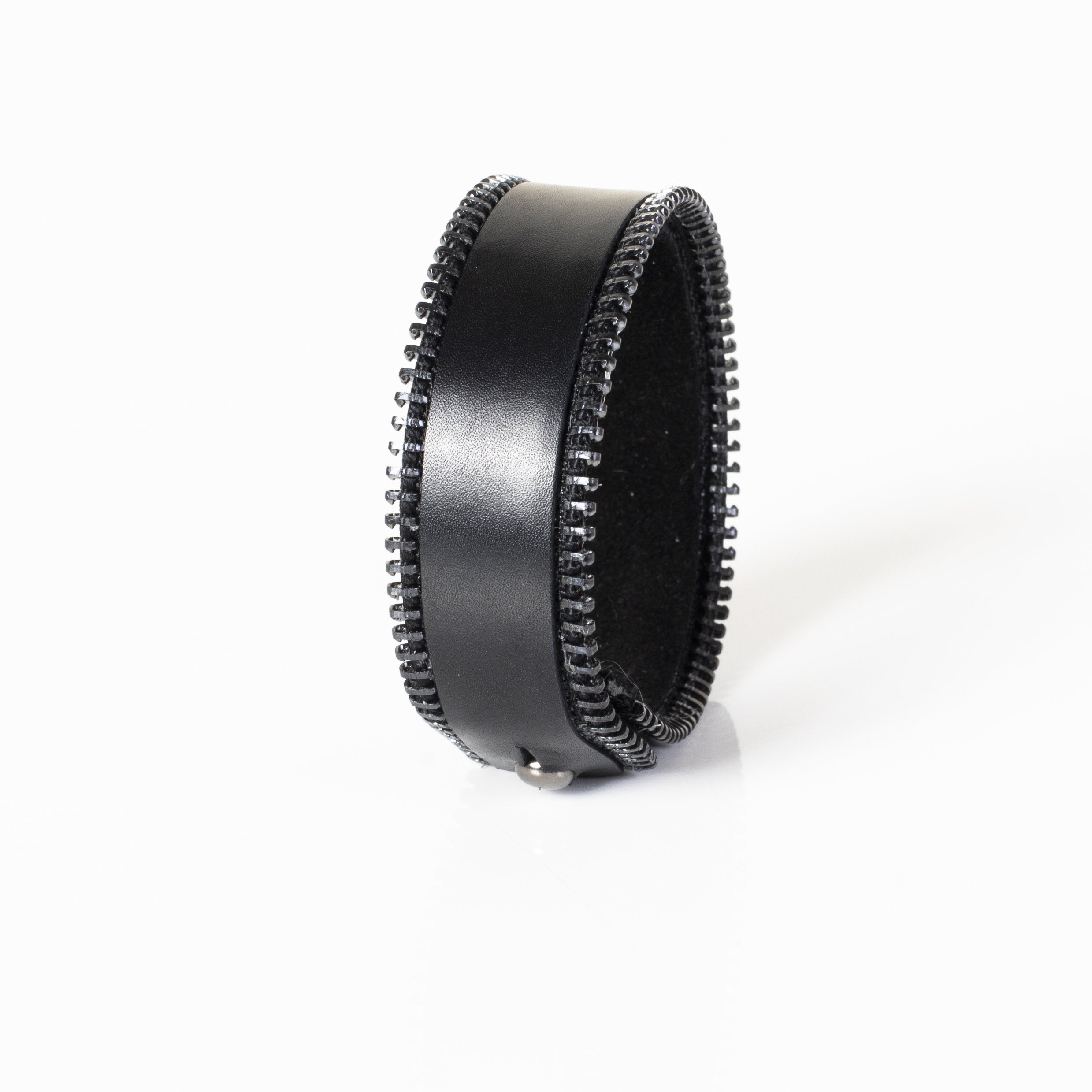 Wide black leather cuff bracelet featuring exposed zipper detailing along both edges in a handcrafted industrial-inspired design.