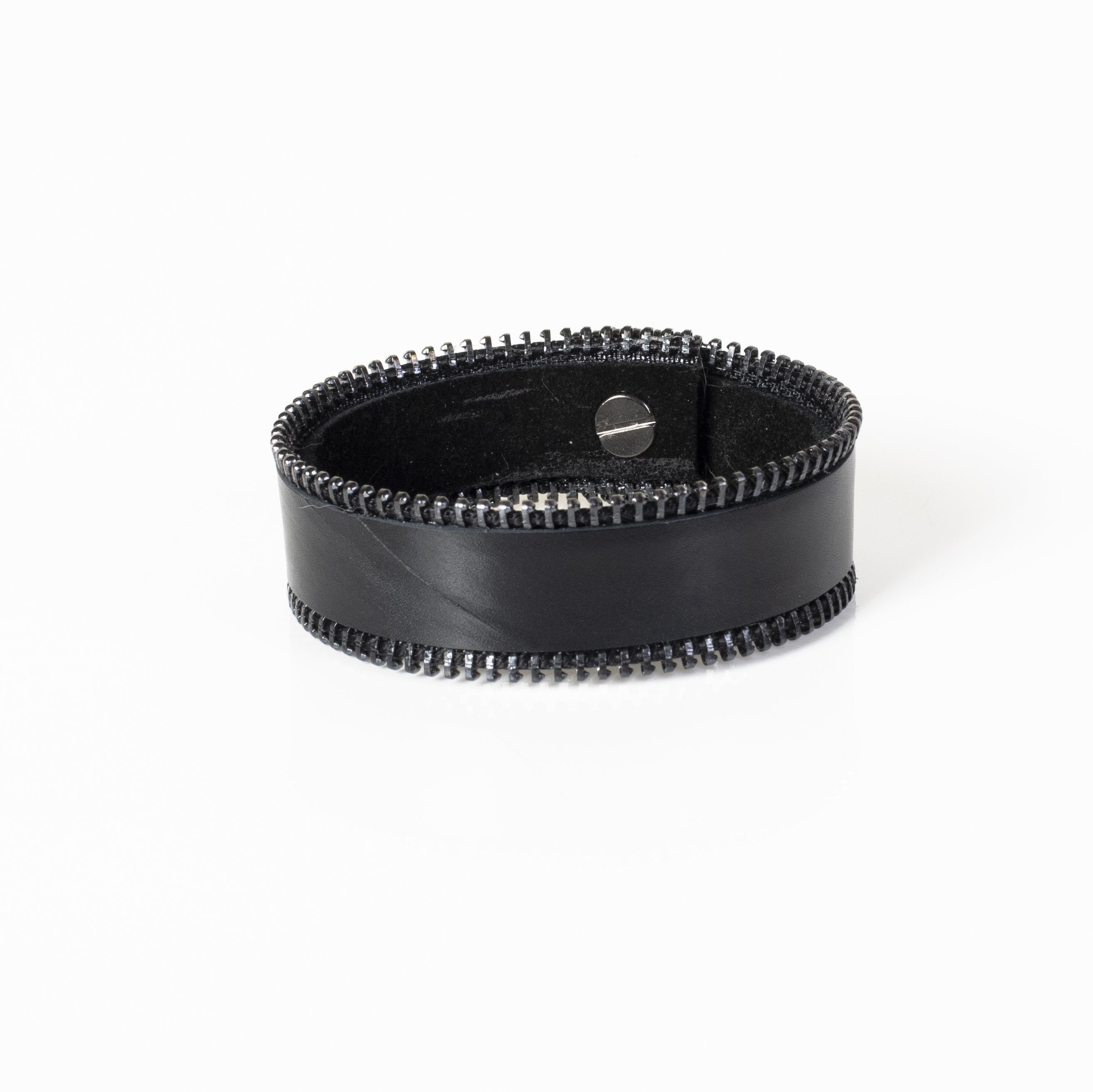 Wide black leather cuff bracelet featuring exposed zipper detailing along both edges in a handcrafted industrial-inspired design.