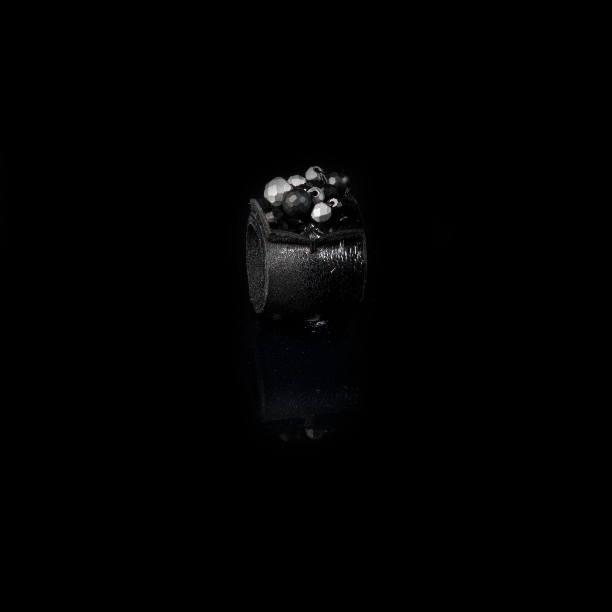 Handmade black leather statement ring with black and silver crystal cluster detail on white background