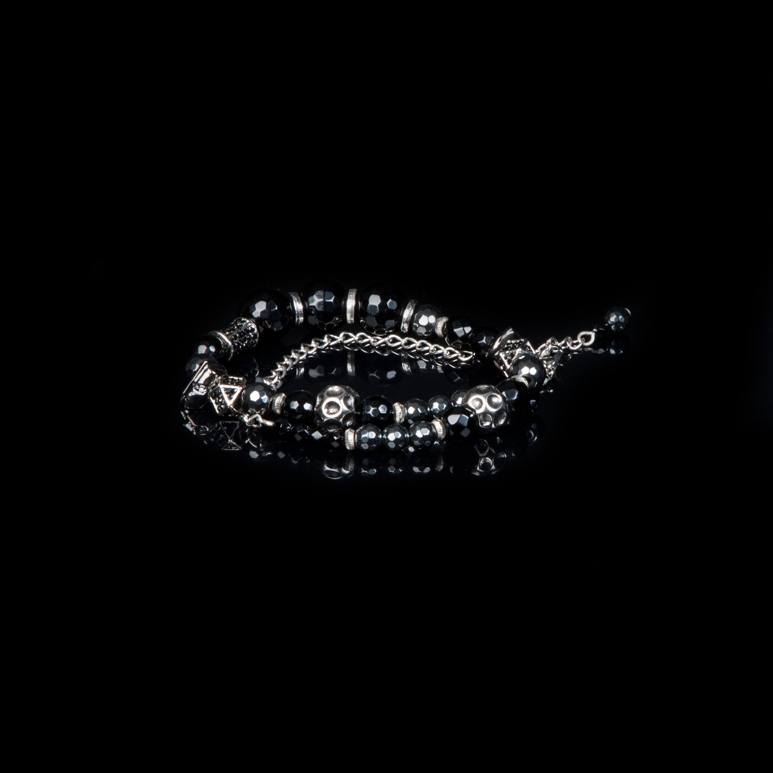 Black crystal beaded bracelet with silver skull charms, smoky marbled stones, and chain accents on white background