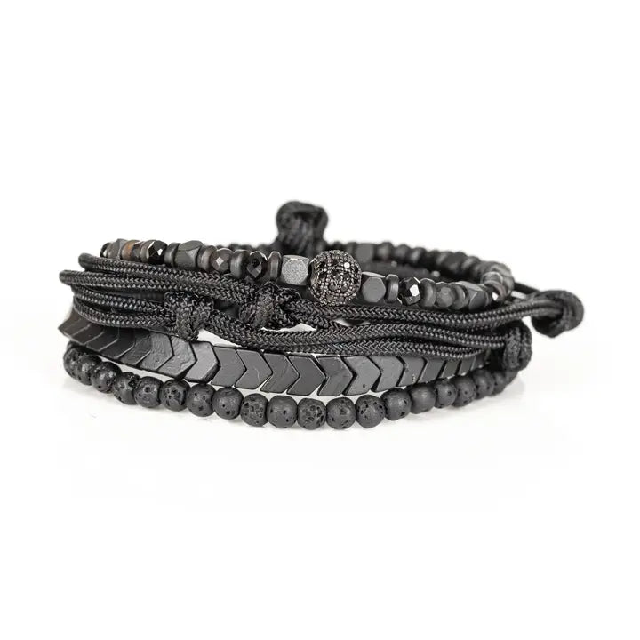 Black layered men’s bracelet set with chevron metal strand, lava stone beads, faceted metallic accents, braided rope wraps, and pavé centerpiece on white background.