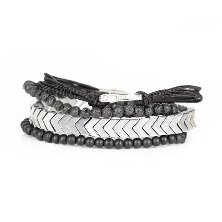 Black and silver layered men’s bracelet set with silver chevron metal strand, lava stone beads, matte black beads, and braided rope wraps on white background.