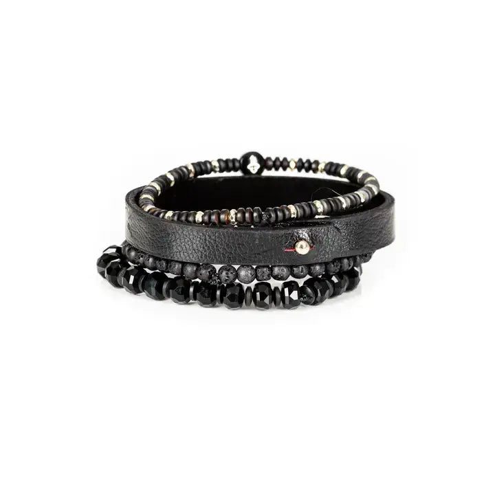Men’s layered bracelet set featuring a black textured leather cuff, matte black lava stone beads, faceted black crystal beads, hematite accents, and a black beaded strand with a cross charm, stacked in a bold modern luxury design on a white background.