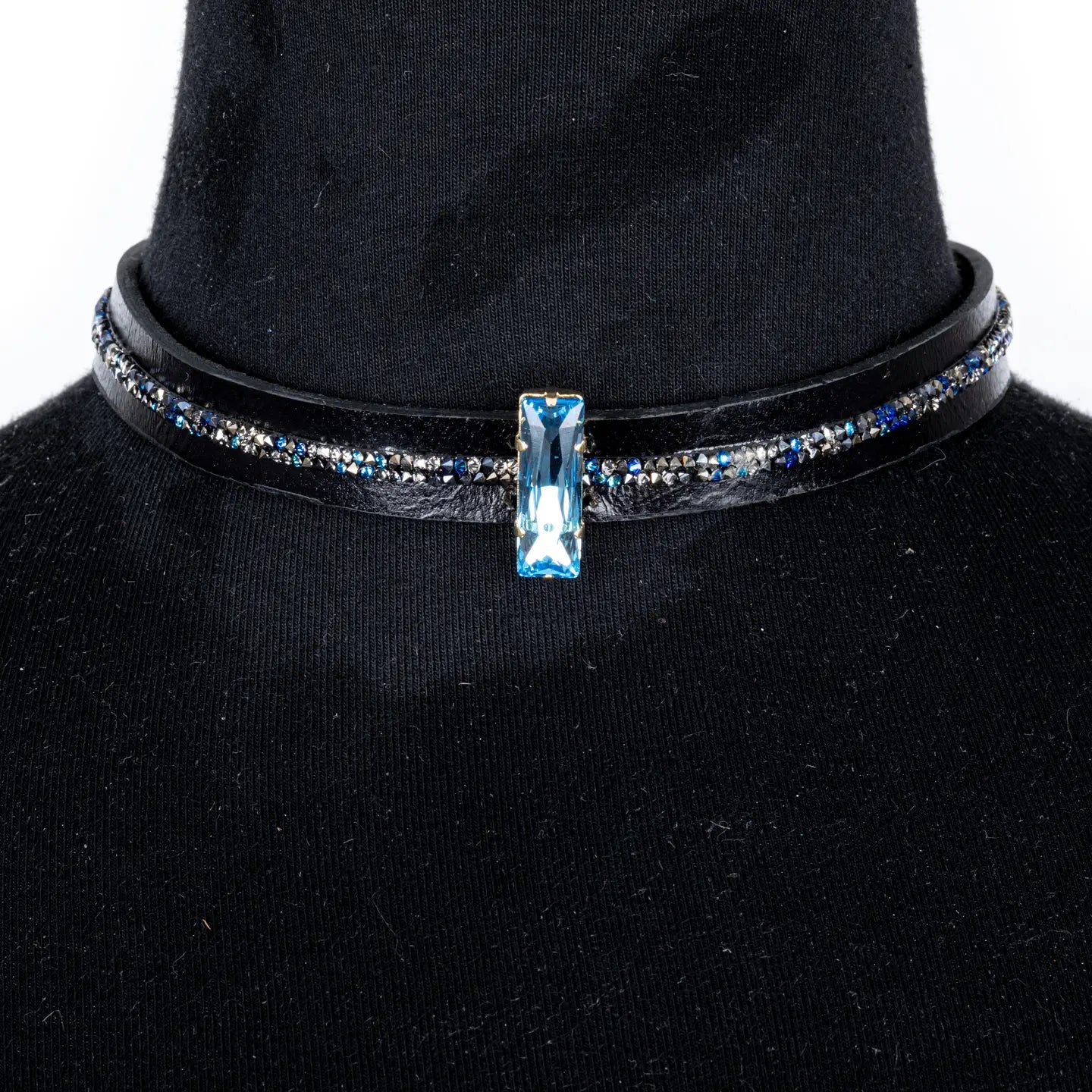 Black leather choker with a central blue crystal and fine rhinestone detailing along the band, displayed on a white background.
