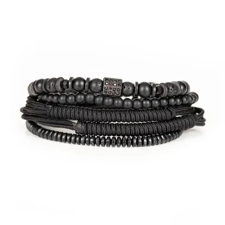 Black layered men’s bracelet set with matte black beads, lava stone accents, braided rope wraps, and dark pavé square detail on white background.