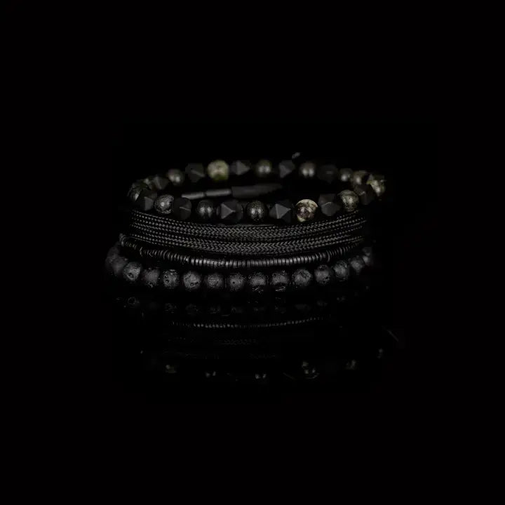 Black multi-layer men’s bracelet set featuring lava stone beads, faceted black onyx stones, braided rope layers, and layered metallic spacer accents on a light background.