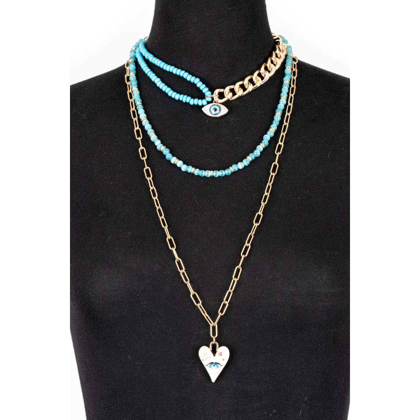 Layered turquoise and gold necklace with evil eye charm and heart pendant on white background.
