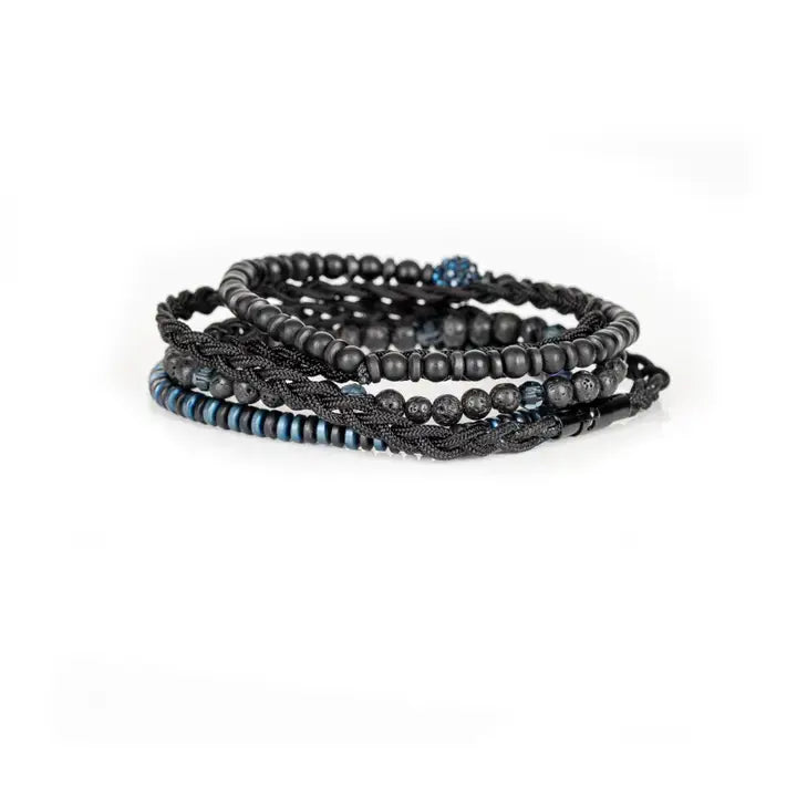 Black and blue multi-layer men’s bracelet featuring braided rope layers, lava stone beads, blue crystal centerpiece bead, faceted crystal accents, and blue metallic disc details on a light background.