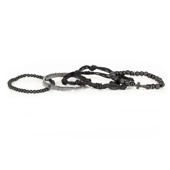 Black layered men’s bracelet set with pavé cross detail, silver chevron metal strand, lava stone beads, matte black beads, and braided rope wraps on white background.