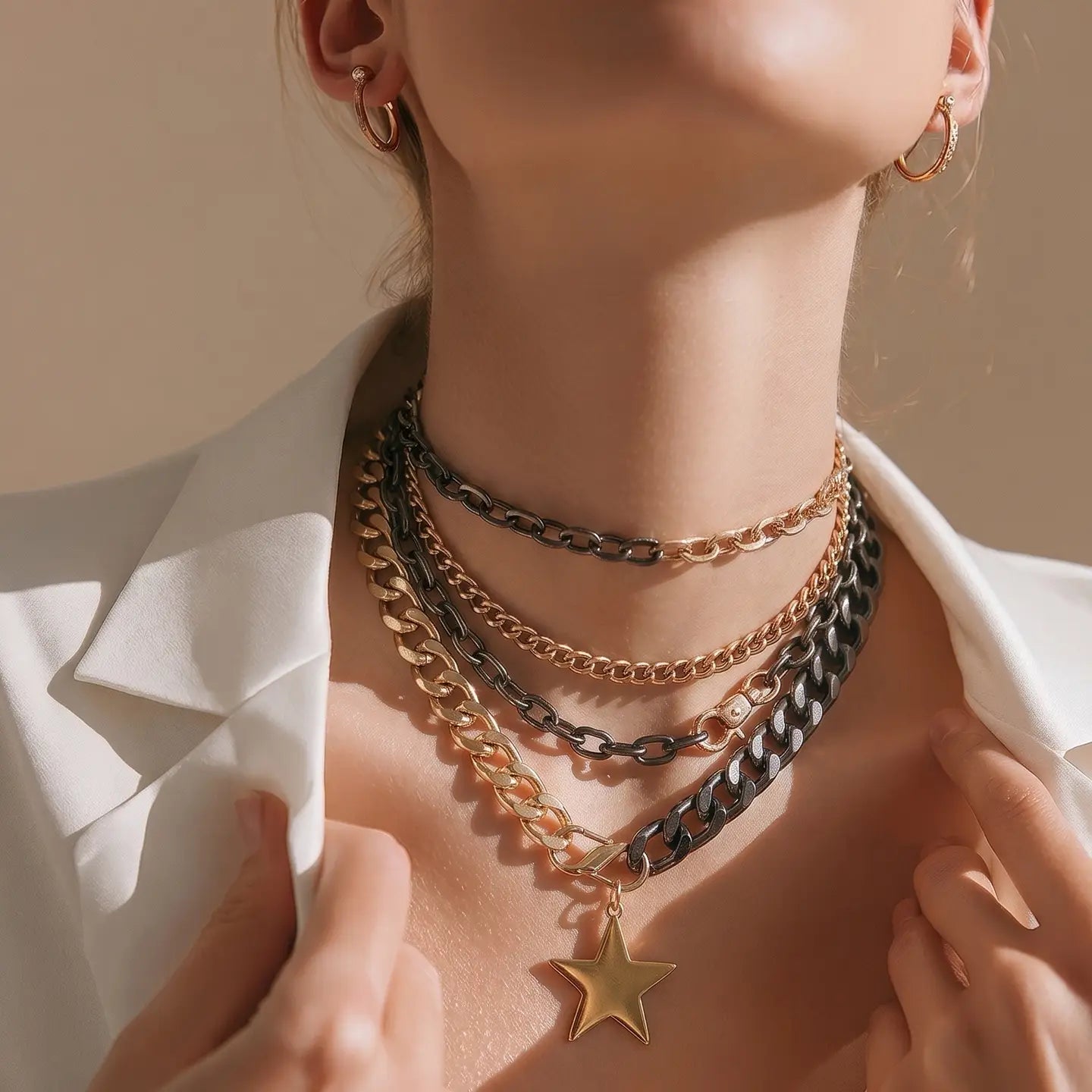 Layered black and gold chain necklace with chunky links and a gold star pendant on a white background.