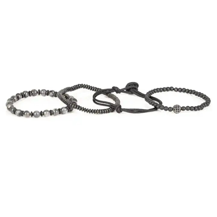 Black and gray layered men’s bracelet set with matte black beads, gray marbled stone accents, braided rope wraps, and pavé centerpiece on white background.