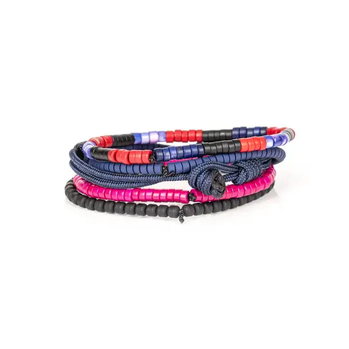 Men’s layered bracelet set featuring navy blue braided cord, blue, black, red, and fuchsia heishi beads, black cube beads, and marbled blue accent beads, stacked in a vibrant contemporary luxury design on a white background.