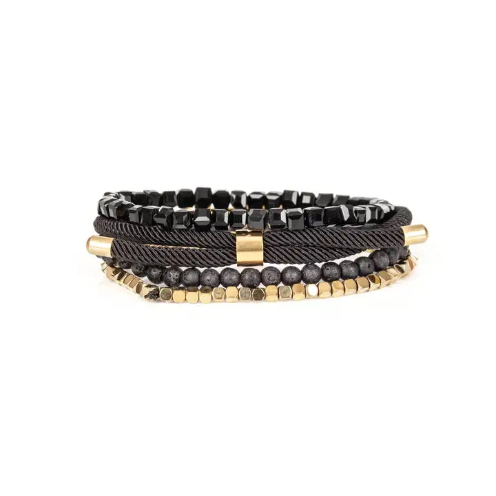 Men’s layered bracelet set featuring faceted black crystal beads, matte black lava stone beads, black braided cord, a polished gold-tone bar centerpiece, and gold-tone hematite-style spacer beads, stacked in a sophisticated black and gold luxury design on a white background.