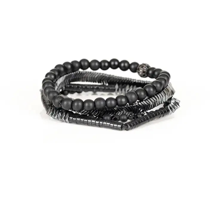 Black multi-layer men’s bracelet featuring matte black onyx beads, silver chevron metal bar, faceted black crystal beads, pyramid-cut hematite accents, and layered metallic details on a light background.