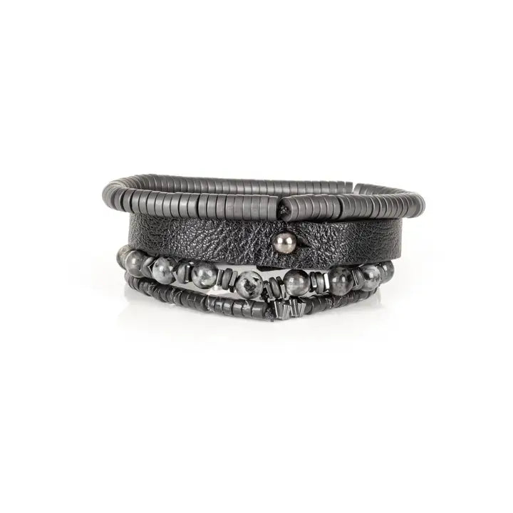 Black multi-layer men’s bracelet featuring textured leather band, gunmetal hematite bead strands, matte grey stone beads, and layered metallic accents on a light background.