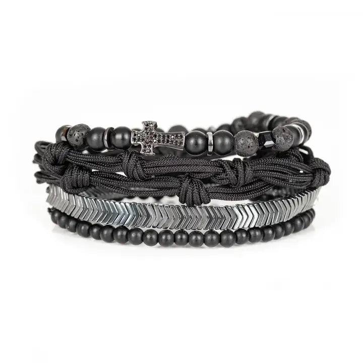 Black layered men’s bracelet set with pavé cross detail, silver chevron metal strand, lava stone beads, matte black beads, and braided rope wraps on white background.