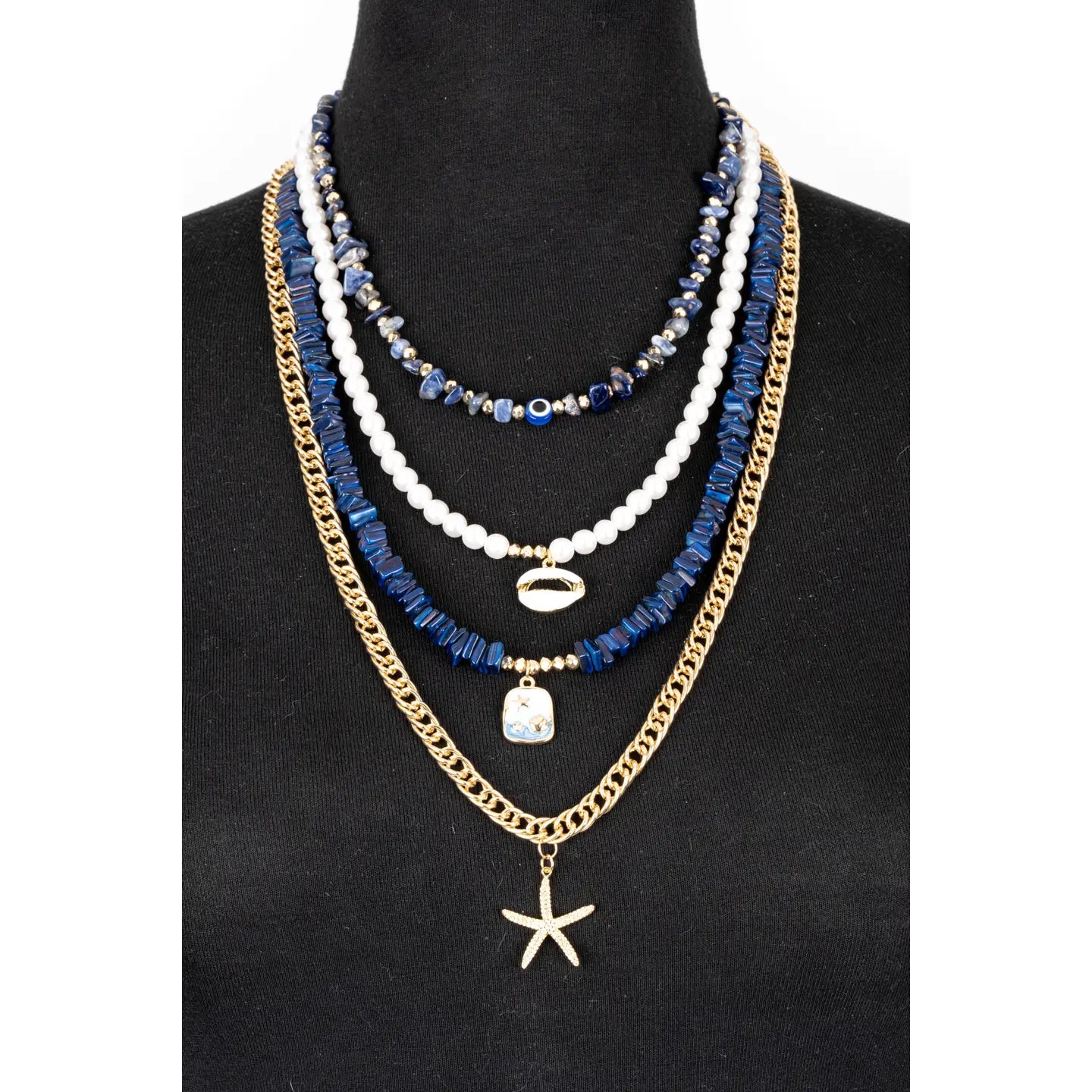 Layered blue and white bead necklace with gold chain and starfish pendant on white background.