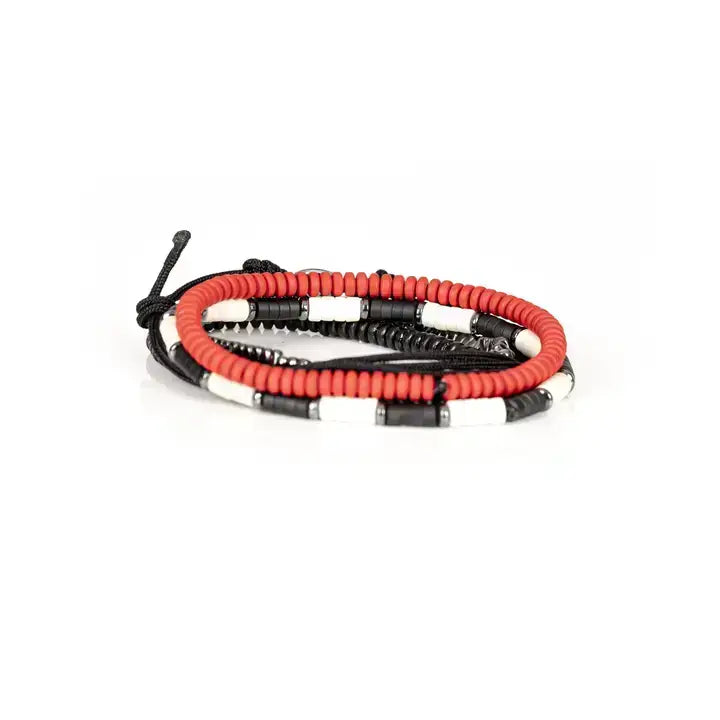 Men’s layered bracelet set featuring coral-red heishi beads, black braided cord wraps, black and white accent beads, faceted hematite crystal beads, black heishi beads, and an evil eye centerpiece, stacked in a bold contemporary bohemian luxury design on a white background.