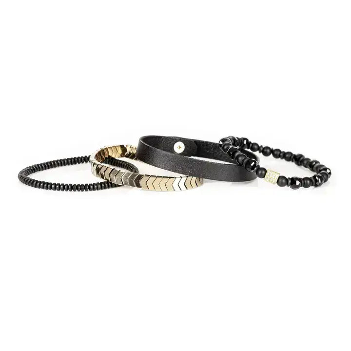 Black multi-layer men’s bracelet featuring faceted black onyx beads, black leather band, gold chevron metal bar, crystal cube accent, and layered metallic bead details on a light background.