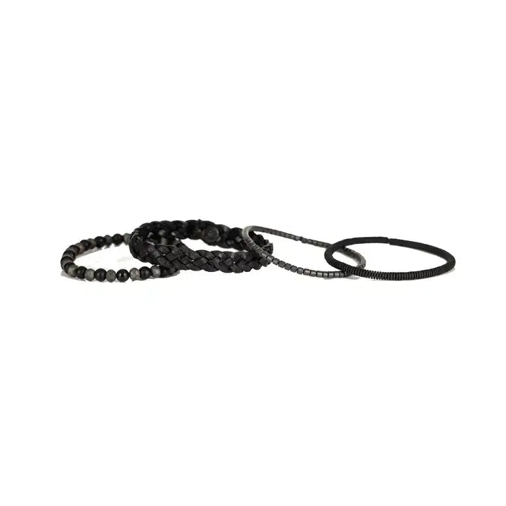 Black multi-layer men’s bracelet featuring braided leather, matte black onyx beads, faceted hematite stones, and layered metallic accents on a light background.