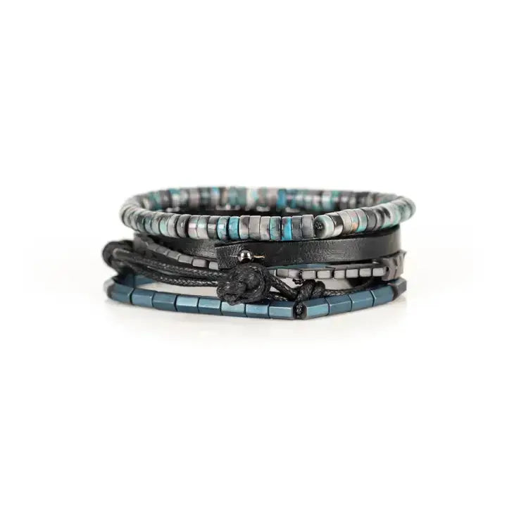 Blue and black multi-layer men’s bracelet set featuring silver chevron metal bar, blue-grey stone beads, black leather band, braided cord, and metallic hematite cube beads on a light background.