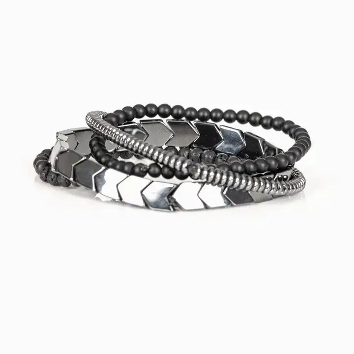 Men’s layered bracelet set featuring gunmetal chevron metal beads, matte black lava stone beads, black matte bead strands, and silver-tone hematite spacer beads, stacked in a bold industrial luxury design on a white background.