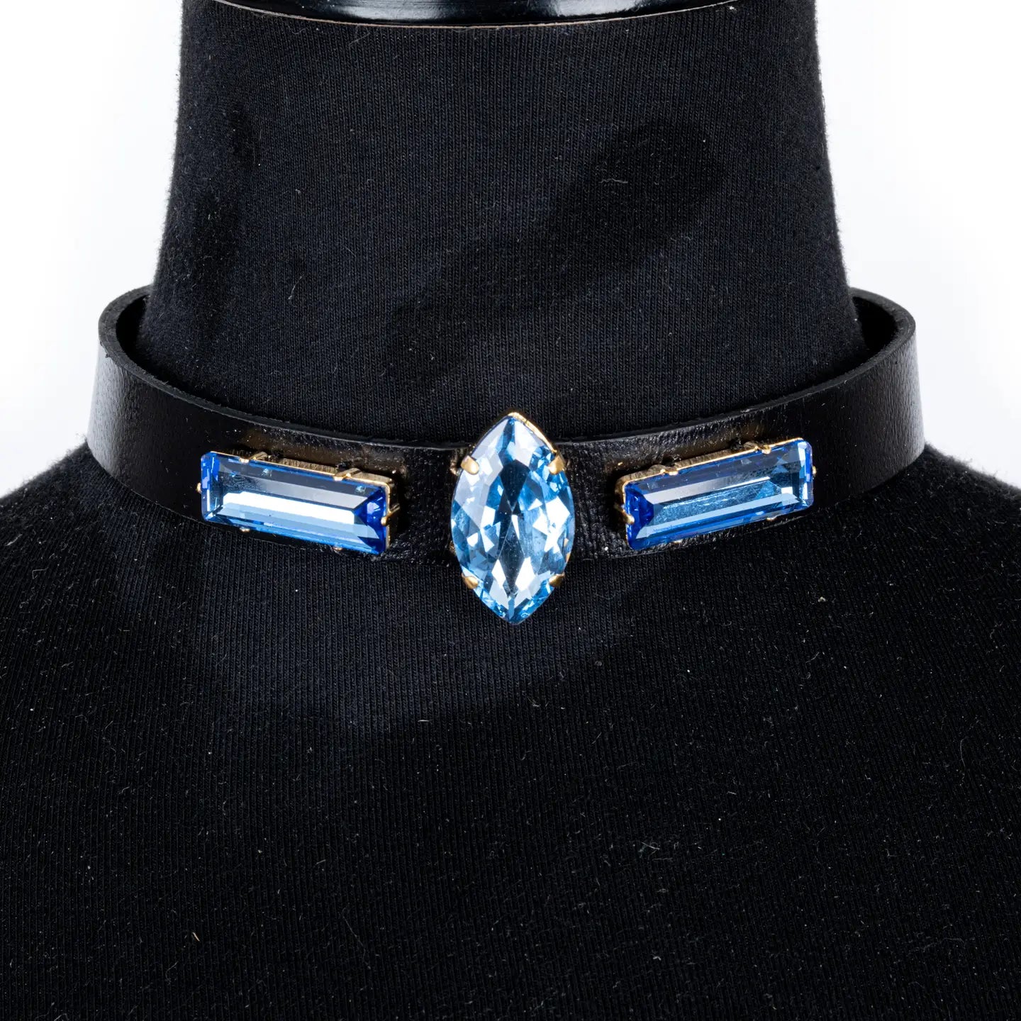 Black leather choker with a central marquise-cut blue crystal and two side baguette blue crystals, displayed on a white background.